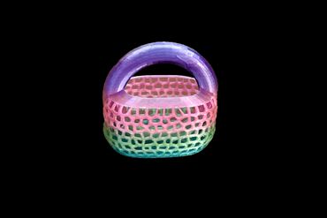 Colorful woven basket with a purple handle on black background.