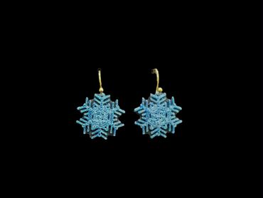Blue snowflake-shaped earrings with gold hooks on a black background.