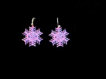 Pink and blue snowflake earrings on a black background.