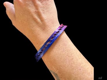 A wrist wearing a purple and blue gradient bracelet with cutout design.