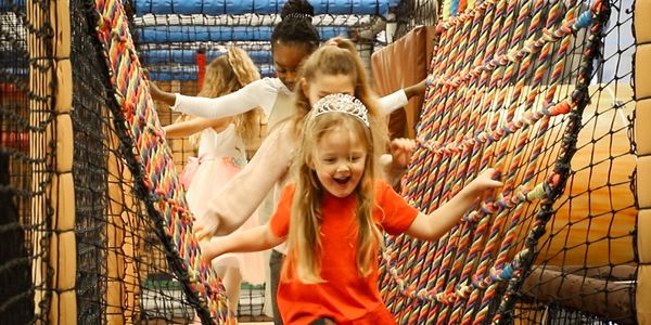 Children walking across the string bridge in the soft play