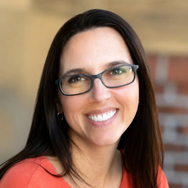 A woman with glasses smiling warmly.