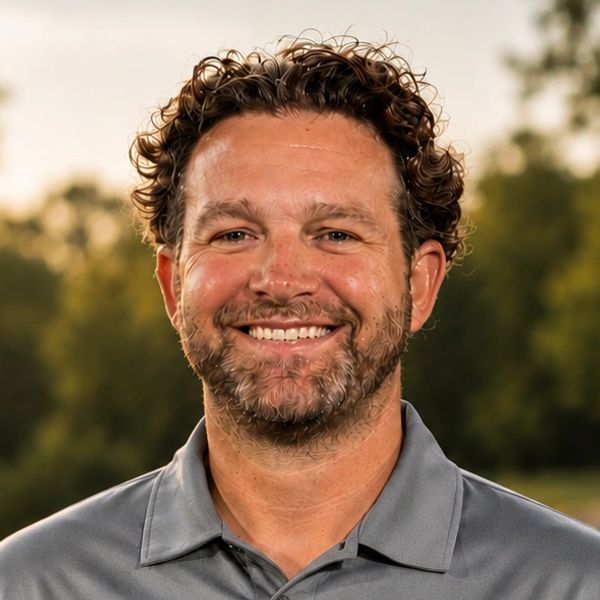 Smiling man with curly hair outdoors.