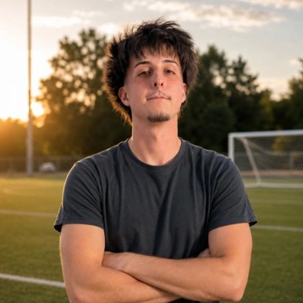 Young man standing on a soccer field at sunset.