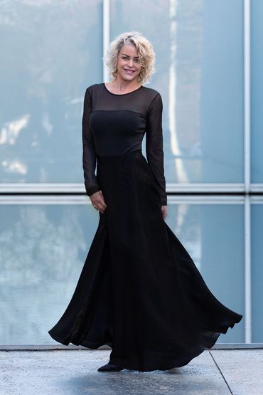 Woman in a long black dress smiling.