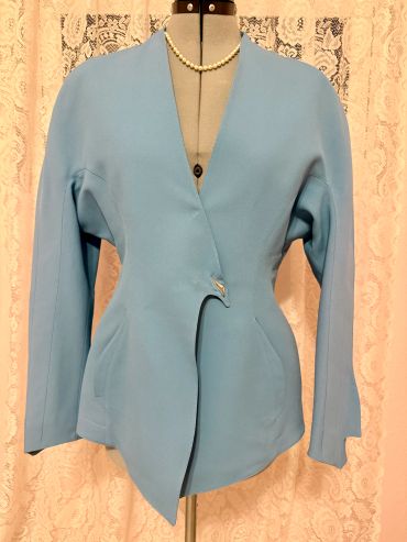 Elegant light blue tailored blazer with a unique asymmetrical hem and pearl necklace.