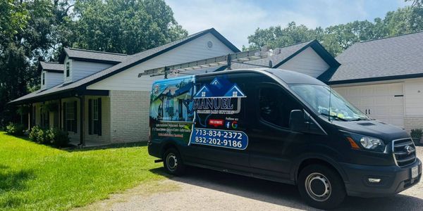Manuel Seamless Rain Gutters service van parked outside a residential home.