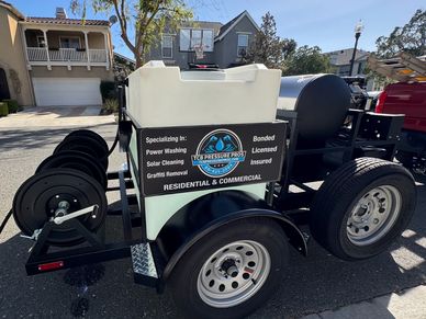 Pressure washing trailer with equipment and company signage.