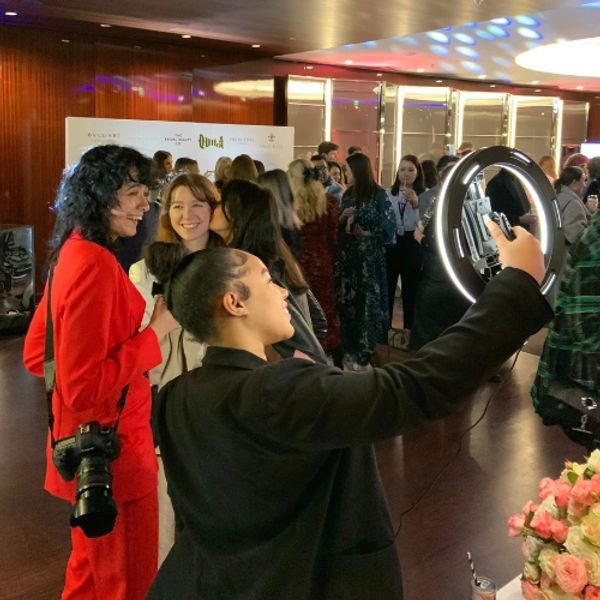 roaming photo booth taking a picture of 3 girls one wearing a red blazer and trousers