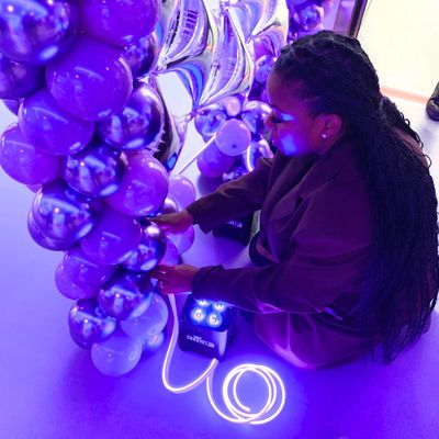 Malvia event stylist setting up balloon decorations using LED rope