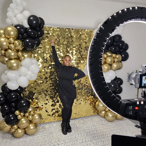 woman posing in front of a gold shimmer wall using a party photo booth