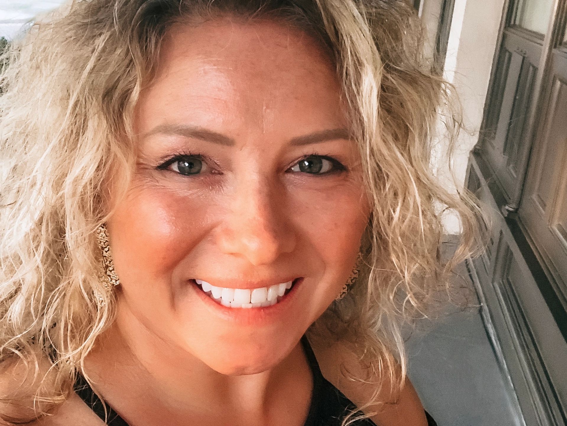 Smiling woman with curly blonde hair.
