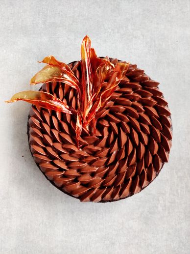 Elegant chocolate cake with intricate frosting and caramel decoration.