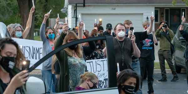 Activists, friends, and family hold candles and signs demanding justice at Andre and Jason's vigil