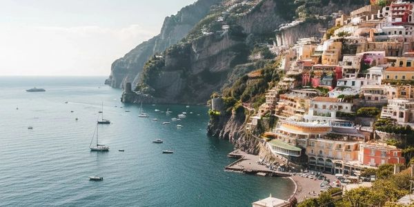 Scenic coastal town with colorful buildings and boats on calm blue water.