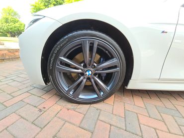 Front wheel and caliper of white BMW 320 cleaned by AM Auto Aesthetics