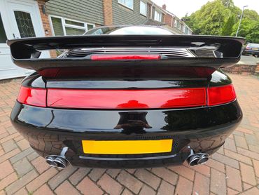 Rear of black Porsche 911 Carrera S with boot gloss and clean exhaust finish