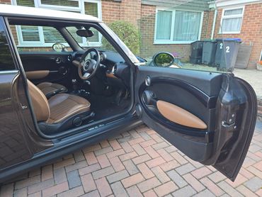 Open car door showing stylish brown and black interior of a Mini Cooper.
