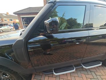 Passenger side of black Range Rover Defender showing polish and tyre shine