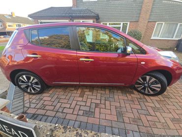 Driver side of red Nissan Leaf showing gloss and clean finish