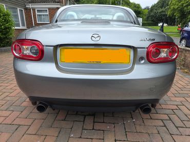 Rear view of a silver Mazda MX-5 sports car with dual exhausts.