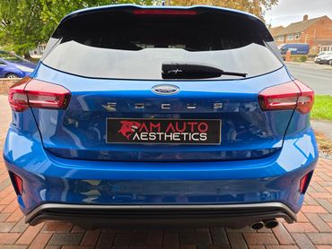 Rear view of a shiny blue Ford Focus hatchback with AM Auto Aesthetics branding.