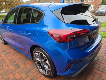 Blue hatchback car parked on a brick driveway.