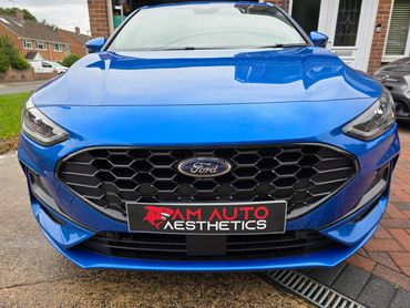 Front view of a blue Ford car with AM Auto Aesthetics plate.