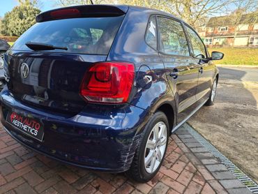 Blue Volkswagen hatchback with rear bumper scratches parked on a driveway.