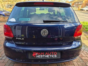 Rear view of a blue Volkswagen Polo with stickers on the rear window.