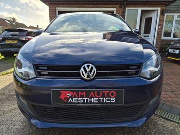 Front view of a polished blue Volkswagen car with AM Auto Aesthetics plate.
