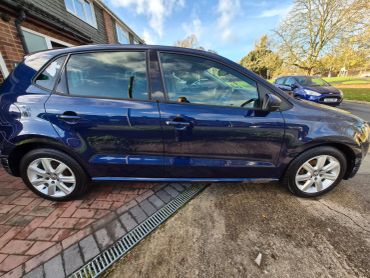 Side view of a blue Volkswagen car parked on a driveway.