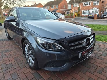Sleek gray Mercedes-Benz parked on a brick driveway in a residential neighborhood.