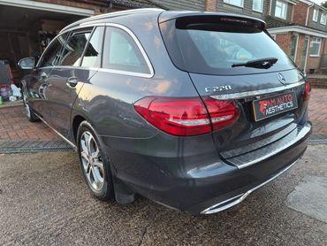 Dark gray Mercedes-Benz C 220 estate car parked outside a house.