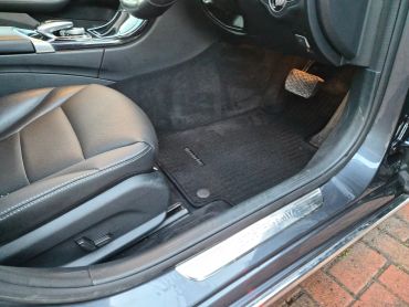 Interior view of a Mercedes-Benz car showing the driver's seat and floor mat.