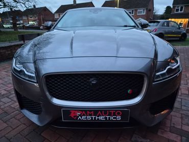 Front view of a sleek gray Jaguar car parked on a driveway.