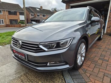 Shiny gray Volkswagen parked on a driveway in a suburban neighborhood.