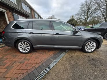 Gray Volkswagen station wagon parked on driveway with overcast sky.