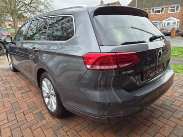 Gray Volkswagen Passat station wagon parked on a brick driveway.