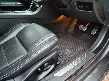 Interior view of a car with black leather seat and pedals.
