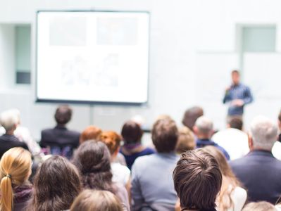 Audience listening to a presentation in a conference room.