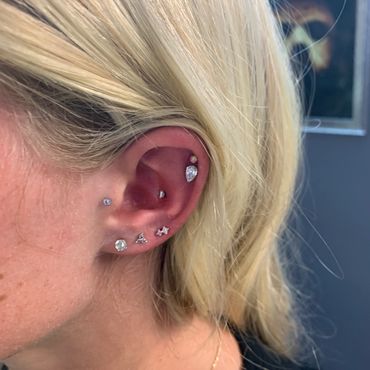 Elegant curated ear piercings featuring a teardrop daith, helix, tragus, and sparkling lobe jewelry.