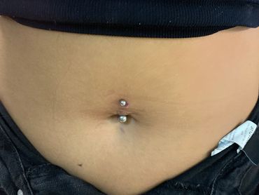 Fresh belly button piercing with a curved barbell and gemstone ends. A timeless body piercing style