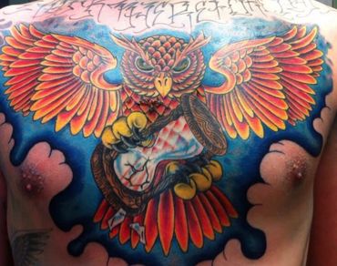 Bold full chest owl tattoo clutching an hourglass, rich with vibrant red, orange, and blue tones.