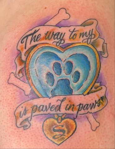 Colorful pet tribute tattoo with heart, paw print, bones, & “The way to my heart is paved in paws.”