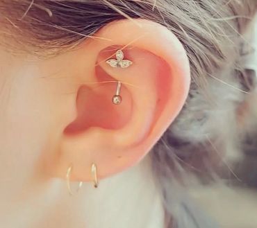 Beautiful curated ear piercings featuring a butterfly gemstone conch stud, vertical barbell.