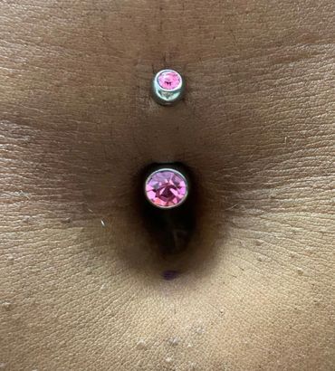 Fresh belly button piercing with a curved barbell and pink gemstone jewelry.