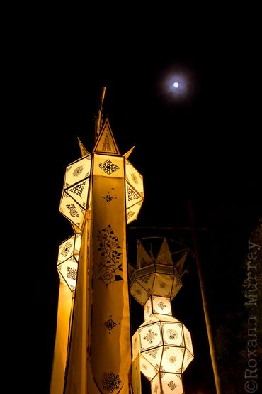 Golden paper lanterns hang with the moon in the sky in Chiang Mai.