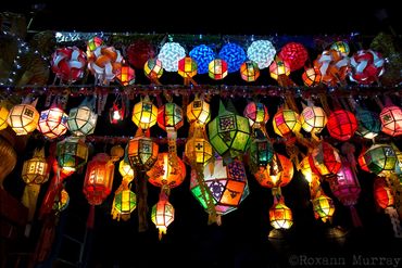 Colorful lanterns hang in a row between buildings during Loi Krathong in Chiang Mai.