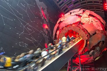 An escalator at the Natural History Museum carries visitors through a brightly lit planet.